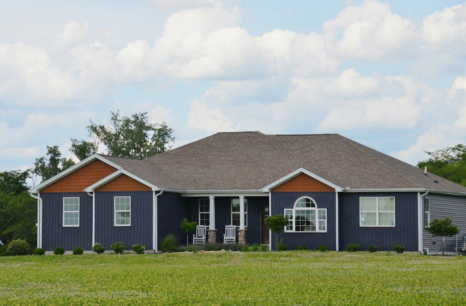 A single-story dark blue house with a green lawn.